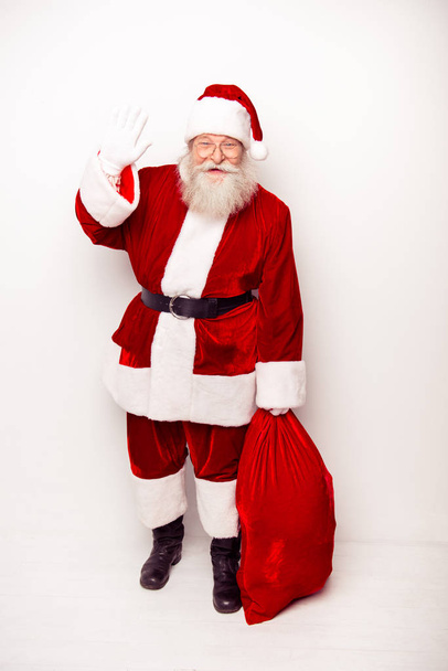 Smiling Santa in traditional costume with sack saying hello - Foto, imagen