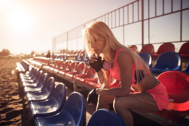 夏の背景に集中的なバレーボール ゲーム、女性ランナー後休んでビーチに座っている魅力的な女性ランナー - 写真・画像