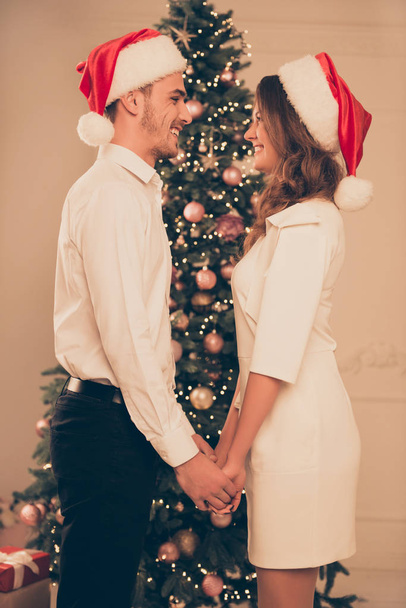 side view portrait of cheerful man and woman in red santa hats h - Foto, imagen