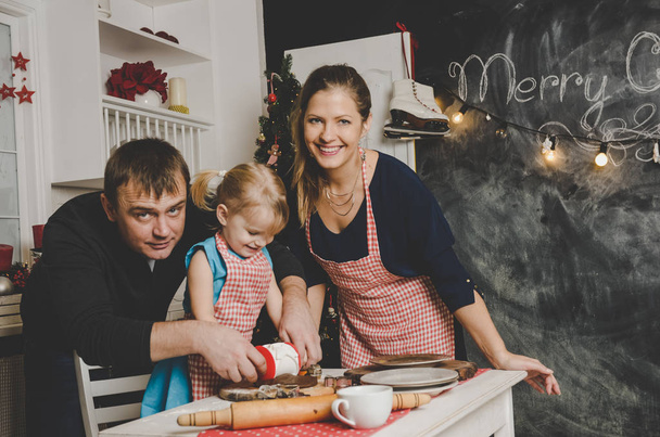Happy family of father mother and little daughter smiling and making cookies  - Fotoğraf, Görsel