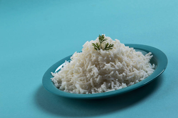 Cooked plain white basmati rice with corriander in a blue plate on blue background - Foto, Bild