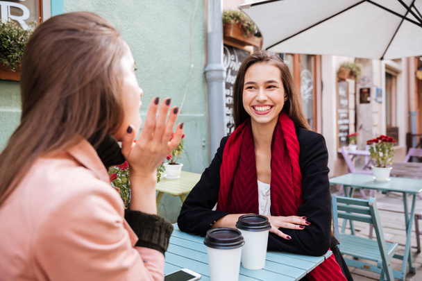 Две веселые женщины разговаривают и смеются в кафе на открытом воздухе
 - Фото, изображение