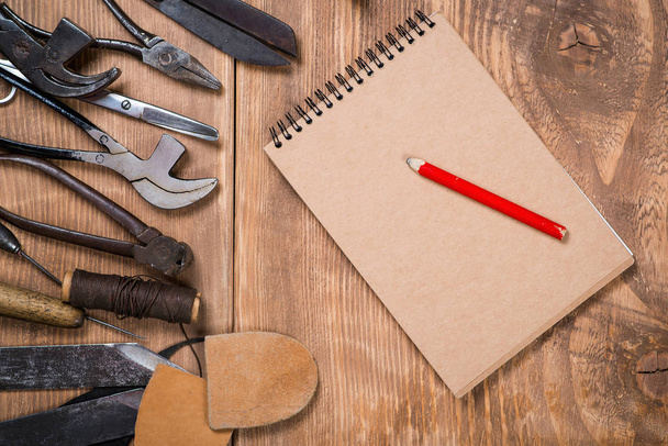 Set of tools, notebook, pencil for shoemaker on a wooden background. - Photo, Image