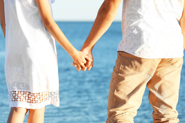 Happy couple holding hands on sea background - Photo, Image