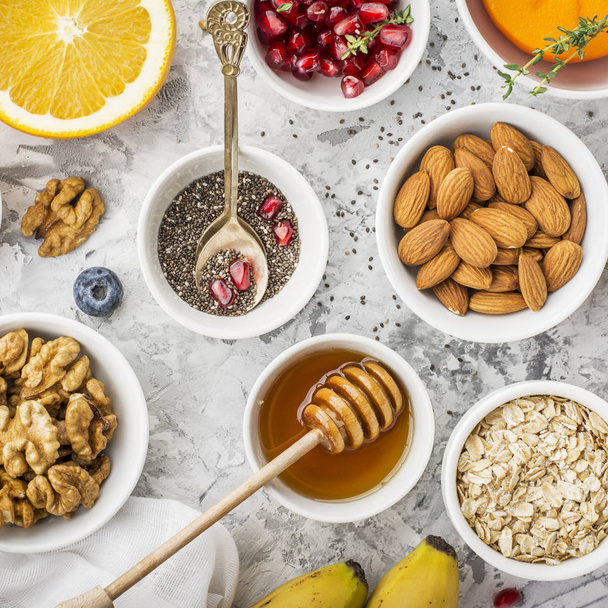Ingredients for a healthy breakfast, nuts, oatmeal, honey, berries, fruits, blueberry, orange, pomegranate seeds, almonds, walnuts The concept of natural organic food in season Top - Photo, image