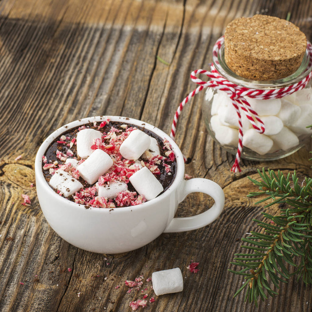 cup of fragrant homemade cocoa with marshmallows and crushed red white candy topping. On the simple wooden textural background. selective focus - Photo, Image