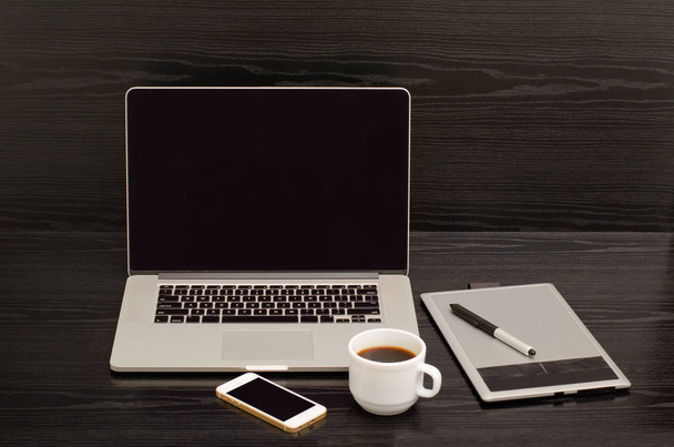 Открыть ноутбук, графический планшет, чашку кофе и телефон на черном столе
 - Фото, изображение