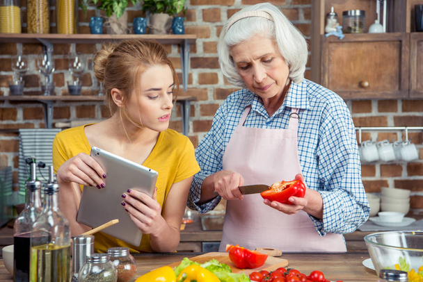 Granddaughter and grandmother cooking together - 写真・画像