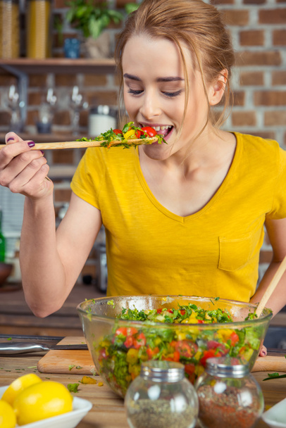 Woman tasting vegetable salad   - Фото, зображення