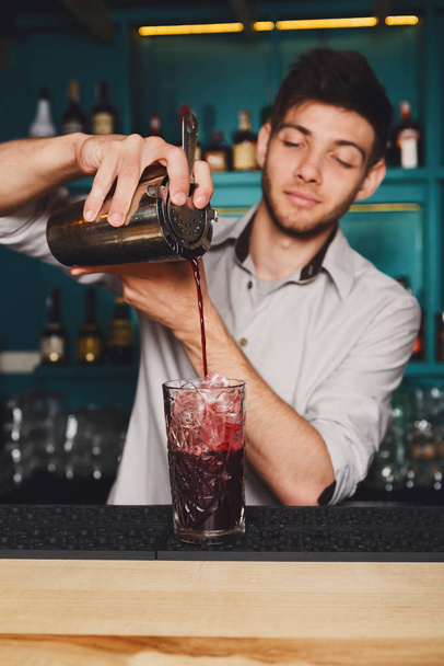 junger gutaussehender Barmann gießt Cocktail-Drink ins Glas - Foto, Bild