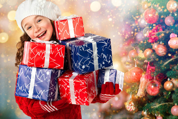 Onnellinen pieni tyttö monia lahjoja lähellä joulukuusi
 - Valokuva, kuva