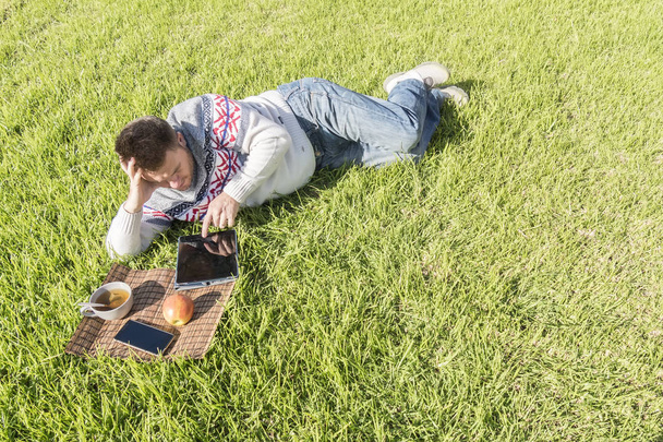 Człowiek o śniadanie, leżąc na trawie w ogrodzie z techn - Zdjęcie, obraz