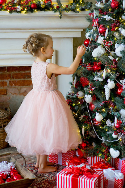 little girl decorating Christmas tree at home - Foto, Bild