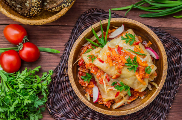 Cabbage rolls in tomato sauce in a bowl. wood background. Top view - Фото, зображення