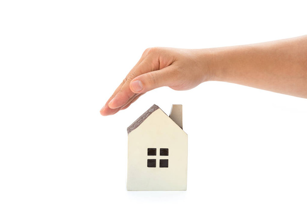 rechte Hand, die ein kleines Einfamilienhaus mit Steckpfad, Wohngebäudeversicherung oder Wohneigentum abdeckt - Foto, Bild
