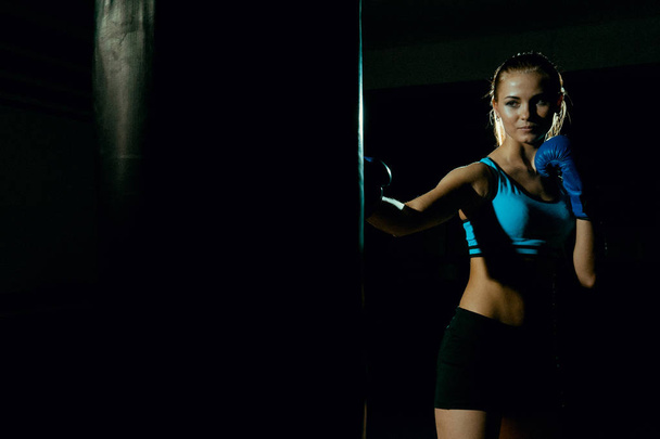 Женщина-боксер с мешком для пунша в действии
 - Фото, изображение