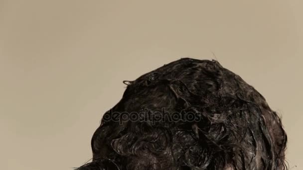 Літня жінка з забарвлення сиве волосся в домашніх умовах, на тлі стіни в бежевий - Кадри, відео