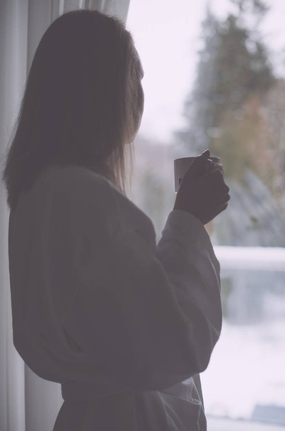 Жінка насолоджується ранковою кавою біля вікна
. - Фото, зображення
