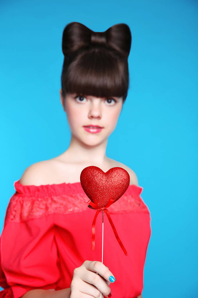 Red heart in teen girl hand. Brunette young model  with bow hair - Foto, Imagem