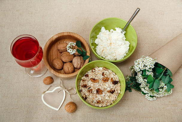 Healthy Organic Breakfast.Walnuts,Oatmeal and Cottage Cheese.Green Ceramic and Wooden Plates.Glass with Red Drink.Wish Heart Card,Bouquet. - Photo, Image
