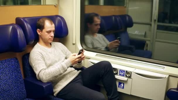 Mies kirjoittaa ja vierittää sovellusta matkapuhelimeensa junassa. Moderni langaton viestintätekniikka. 4K-video
 - Materiaali, video