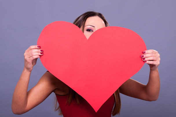 Woman wearing red dress holding big heart sign love symbol  - Foto, imagen
