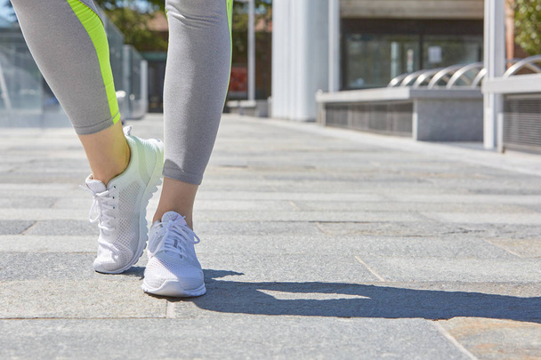 Woman with white sport shoes ready to run outdoor in the city, sunny day - Фото, зображення