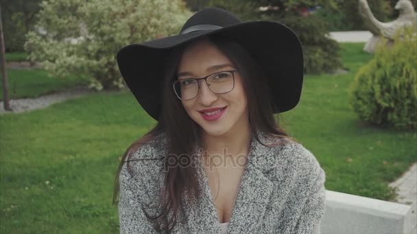 Close up retrato de mulher bonita em chapéu preto e óculos no parque ao ar livre
 - Filmagem, Vídeo