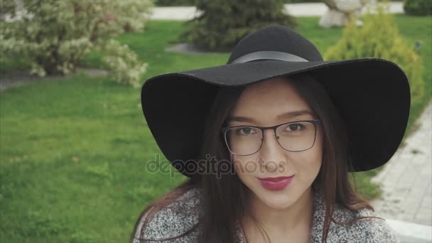 Крупним планом портрет досить усміхненої жінки в чорному капелюсі і окулярах в парку
 - Кадри, відео