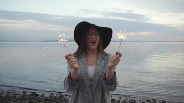 Όμορφη γυναίκα άλματα και πανηγυρισμούς με βεγγαλικά στην παραλία το ηλιοβασίλεμα - Πλάνα, βίντεο