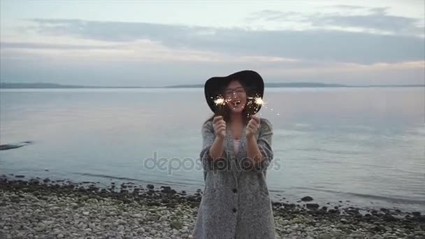 Bardzo szczęśliwą kobietą radości ognie na brzegu rzeki o zachodzie słońca - Materiał filmowy, wideo