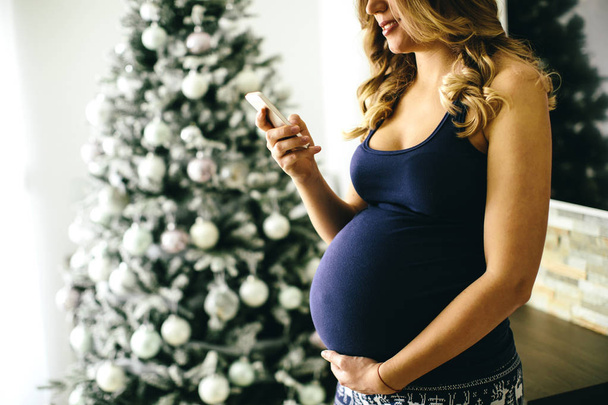Pregnant woman with smartphone at Christmas - Photo, image