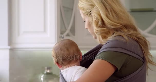 Busy Mother With Baby In Sling  - Materiał filmowy, wideo