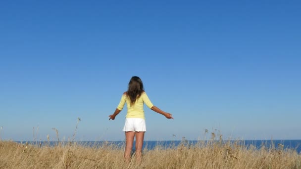 4K. Woman in yellow blouse have lift hands against sea. Approach of focus - Footage, Video