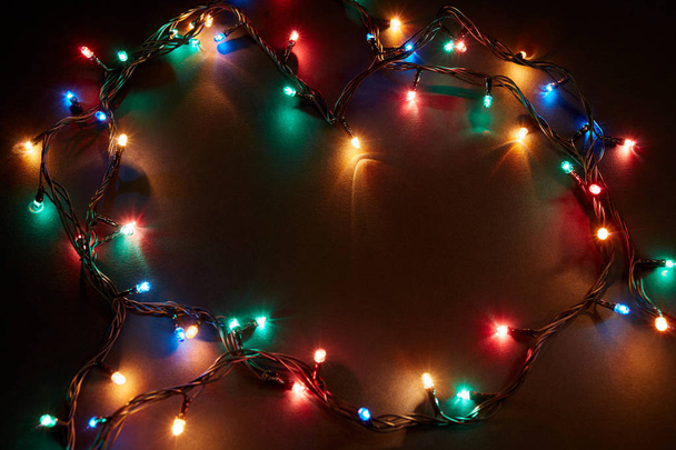ライトと無料のテキストスペースでクリスマスの背景。クリスマスライトの境界線。黒を背景にカラフルなクリスマスライトを輝きます。新年。クリスマスだ。装飾品だ。ガーランド. - 写真・画像