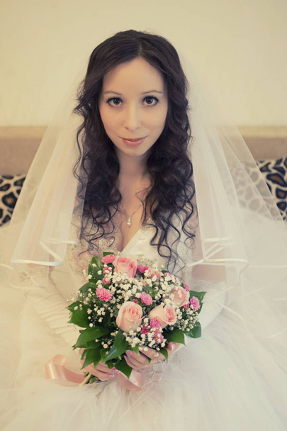 Mooie gelukkige bruid in haar trouwjurk zit - Foto, afbeelding