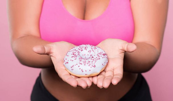 Close up of plump woman holding tasty donut - Foto, imagen