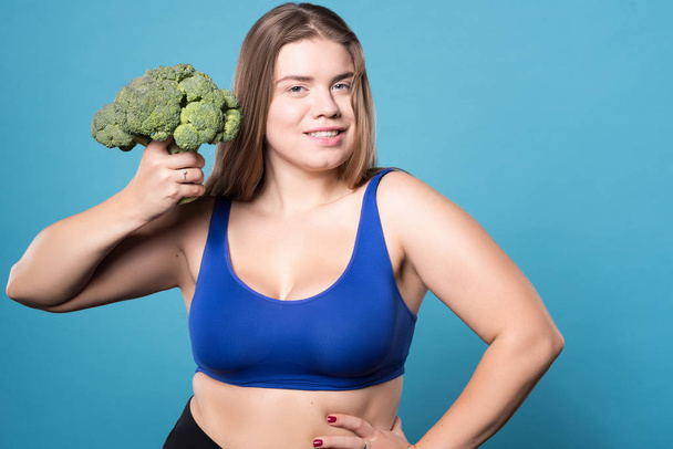 Pleasant plump woman holdign broccoli - Fotoğraf, Görsel
