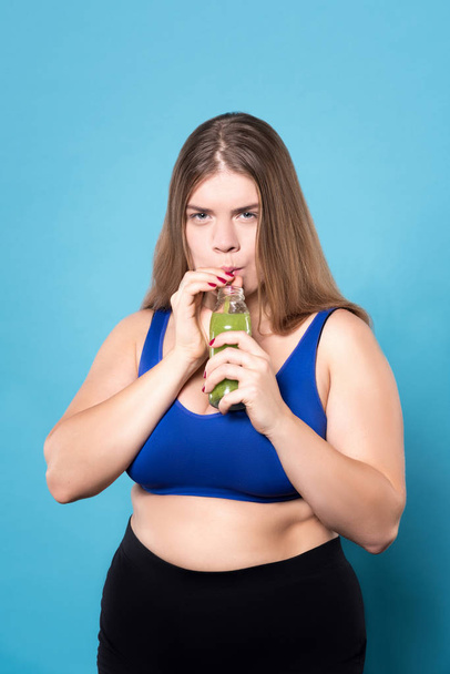 Plump woman drinking green beverage - Foto, Imagem