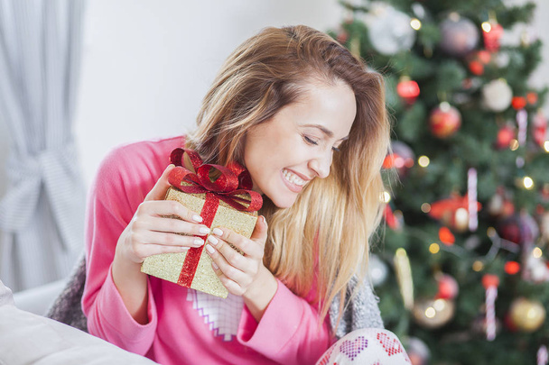 woman on the sofa holding a Christmas present - Foto, imagen