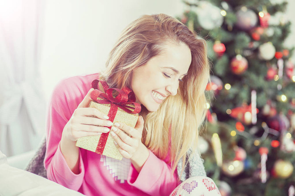 woman on the sofa holding a Christmas present - Фото, изображение