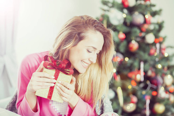 woman on the sofa holding a Christmas present - Foto, Imagen