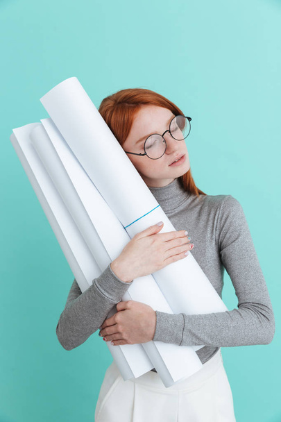 Tired young woman with closed eyes holding and huging blueprints - Fotoğraf, Görsel