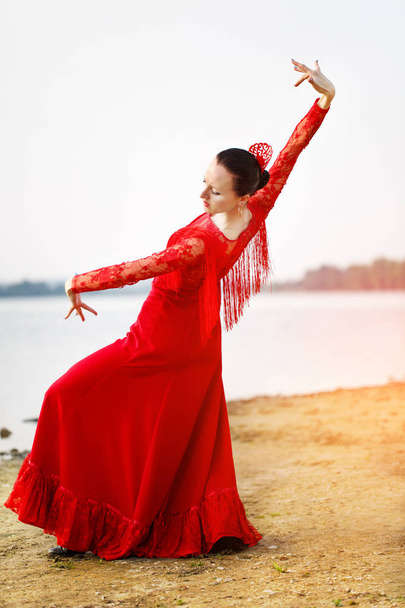 Woman in long red dress stay in dancing pose - Фото, изображение