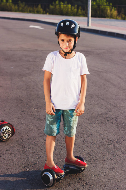 Мальчик стоит на черном мотороллере на улице
 - Фото, изображение