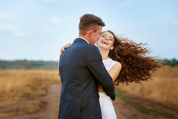 happy bride and groom walking in a field in wedding day - Foto, afbeelding