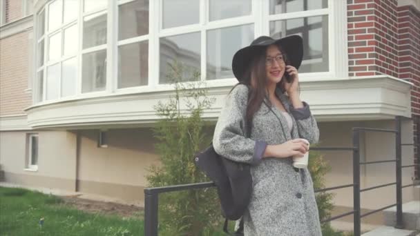 attraktive Geschäftsfrau mit schwarzem Hut und Brille telefoniert - Filmmaterial, Video