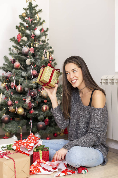 woman next to Christmas tree with with a gift - Zdjęcie, obraz
