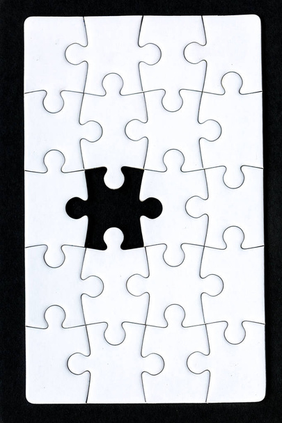 um quebra-cabeça que falta uma peça contra um fundo preto
 - Foto, Imagem