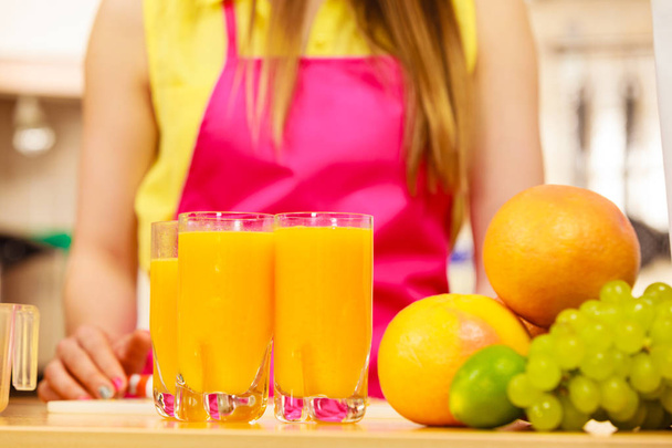Woman with fresh fruits and juice in kitchen - Zdjęcie, obraz
